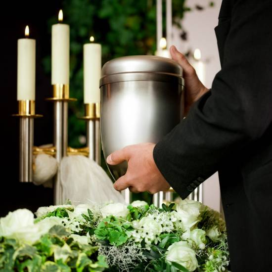 death and dolor  - funeral and cemetery, mortician carrying the urn to a bed of white roses